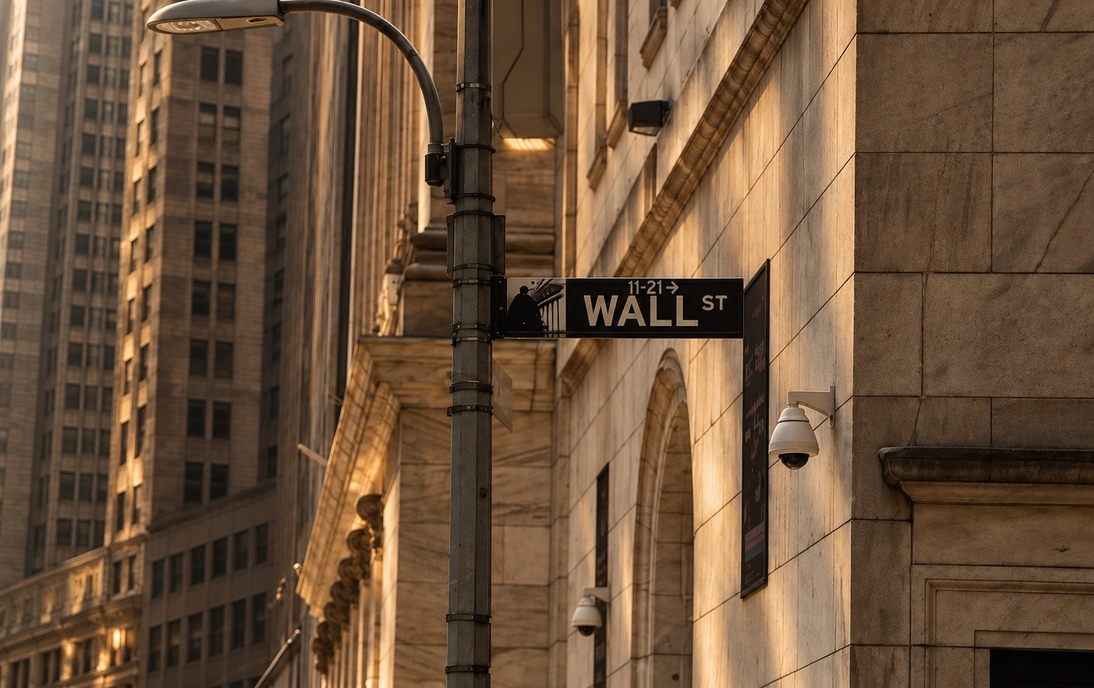 Wall Street sign illuminated by warm golden light in Manhattan’s financial district, representing Empire Holding’s focus on investment, capital and global opportunity.