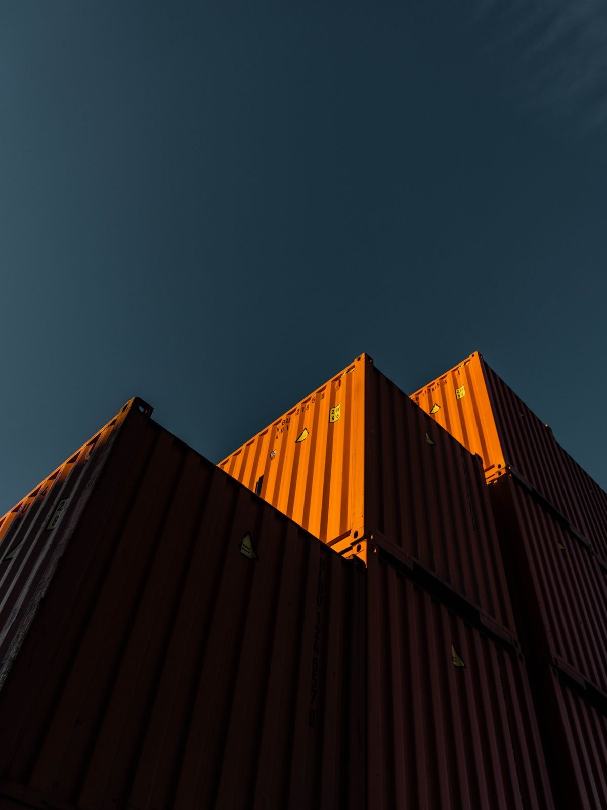 Stacked shipping containers illuminated by warm sunlight, representing logistics, trade and infrastructure within Empire Holding’s diversified business portfolio.