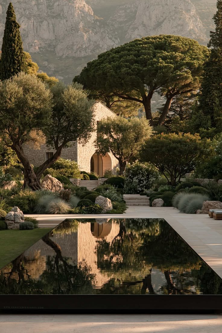 Luxury stone villa surrounded by mature Mediterranean-style landscaping, with a reflective pool, sculpted gardens and dramatic mountain scenery.